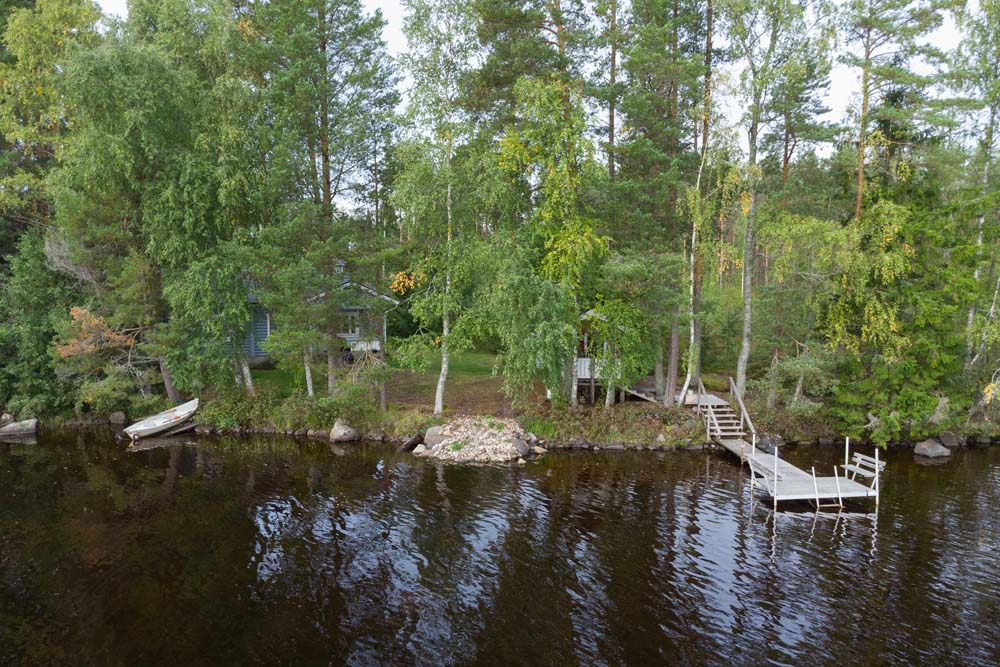 Kannonjärven rannalla on laituri, soutuvene ja metsäinen mökkipiha.