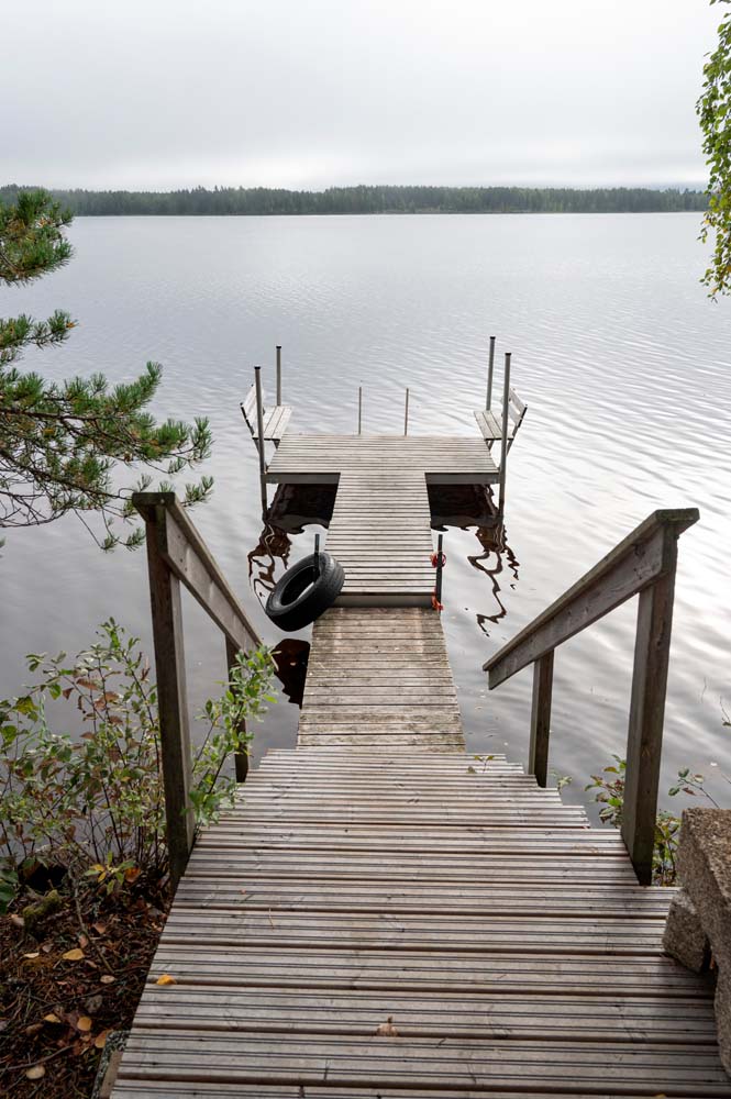 Puinen laituri ja soutuvene tyynellä Kannonjärvellä metsämaiseman keskellä.