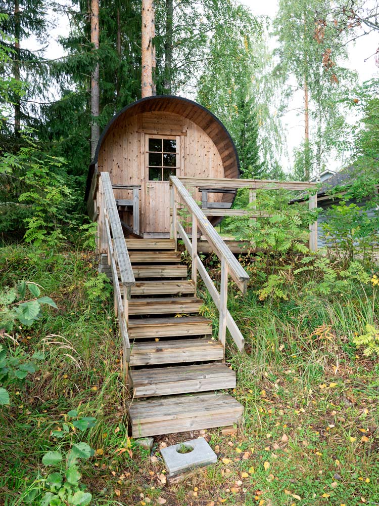 Puurakenteinen mökki metsän keskellä, jonne johtaa jyrkät portaat.